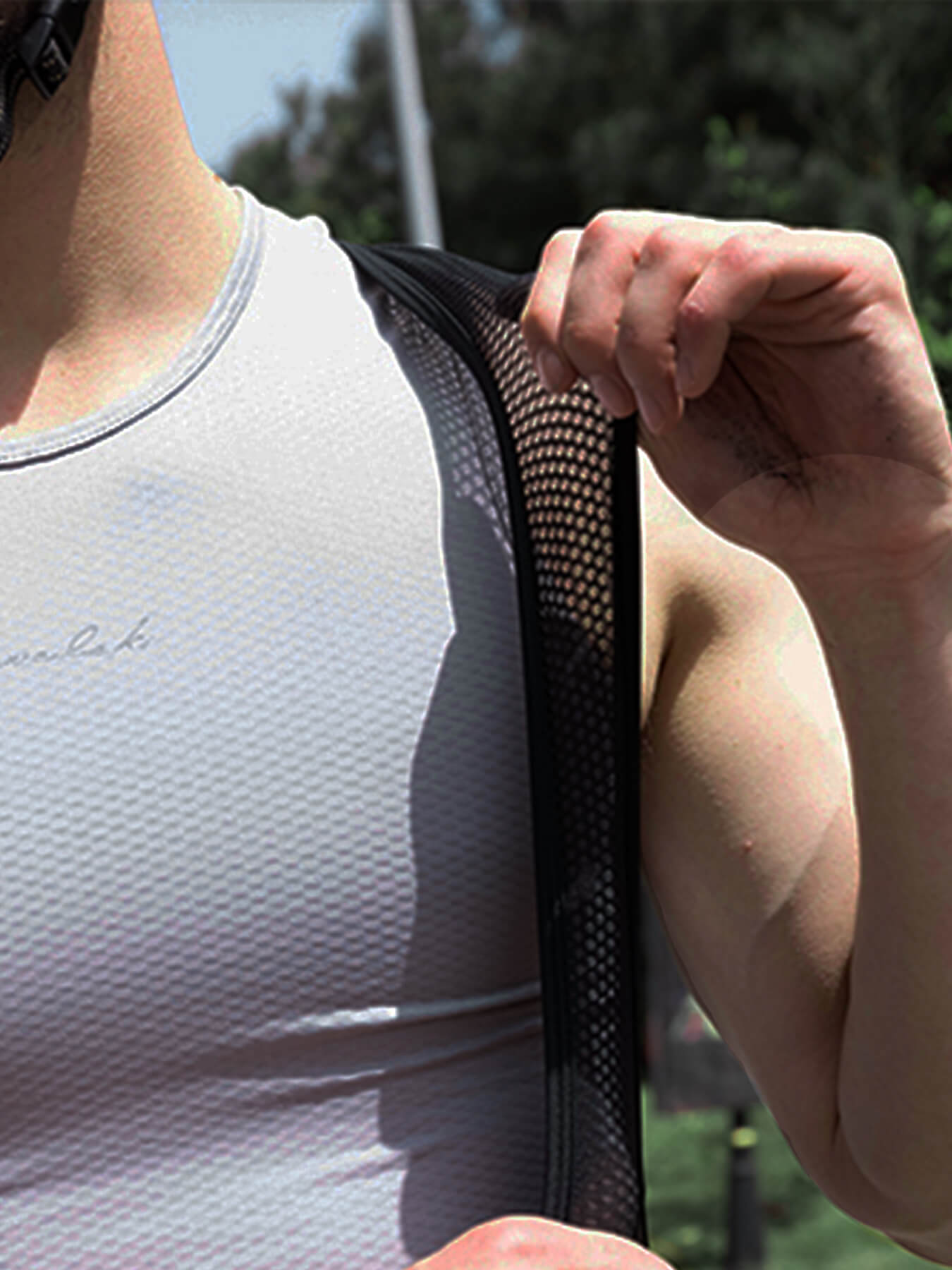 Black cycling bib shorts mesh shoulder panel being adjusted by hand